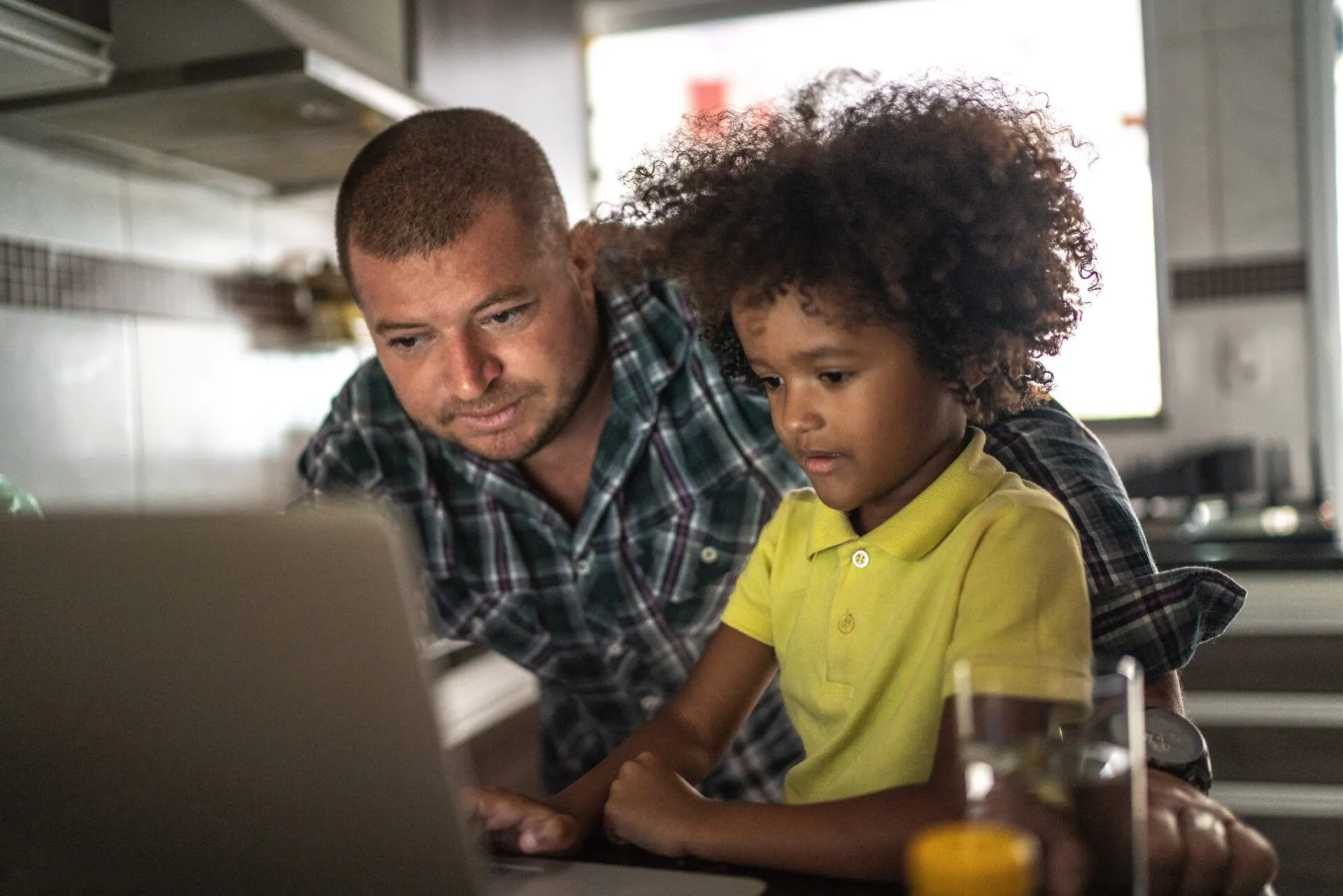 Dad looking at laptop with young son