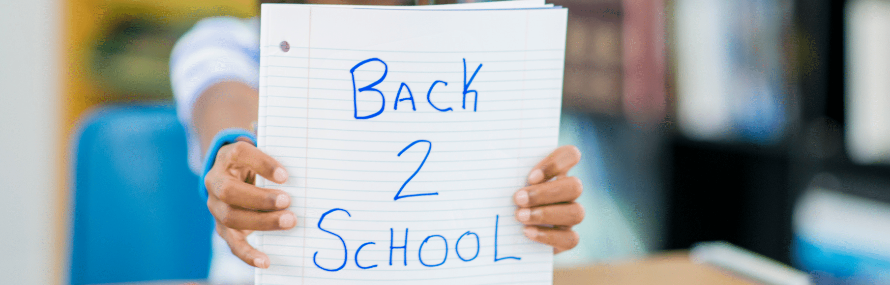 Girl Holding Up Paper with Back 2 School written in blue marker