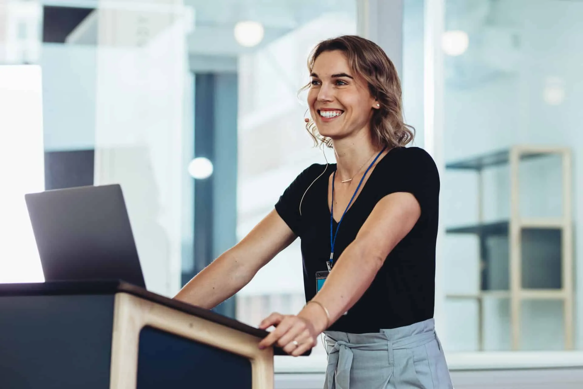 Businesswoman standing at podium with laptop and smiling. Successful female business professional addressing a conference