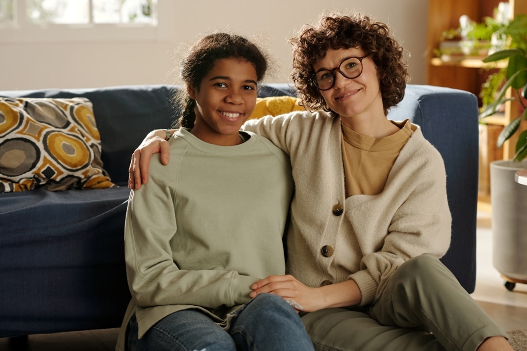 White adoptive mom with arm around mixed race teen adopted daughter