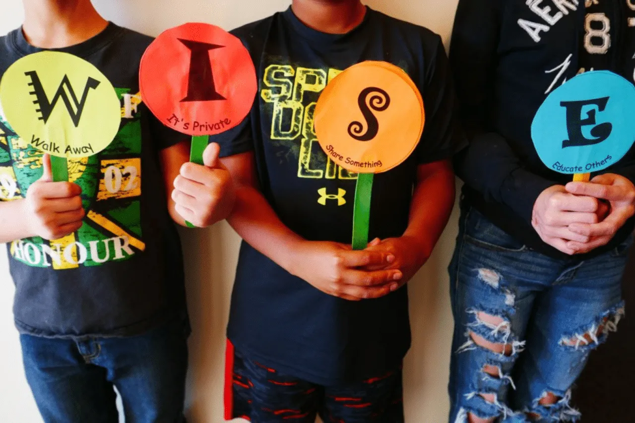 Kids holding up circle paper signs on popsicle sticks with letters W I S E