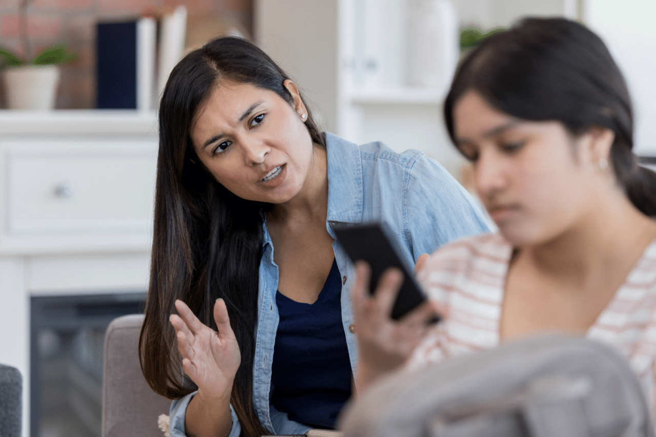 Mom trying to talk to teenage daughter looking at phone