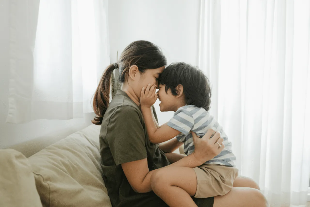 Mom hugging younger son smiling touching faces