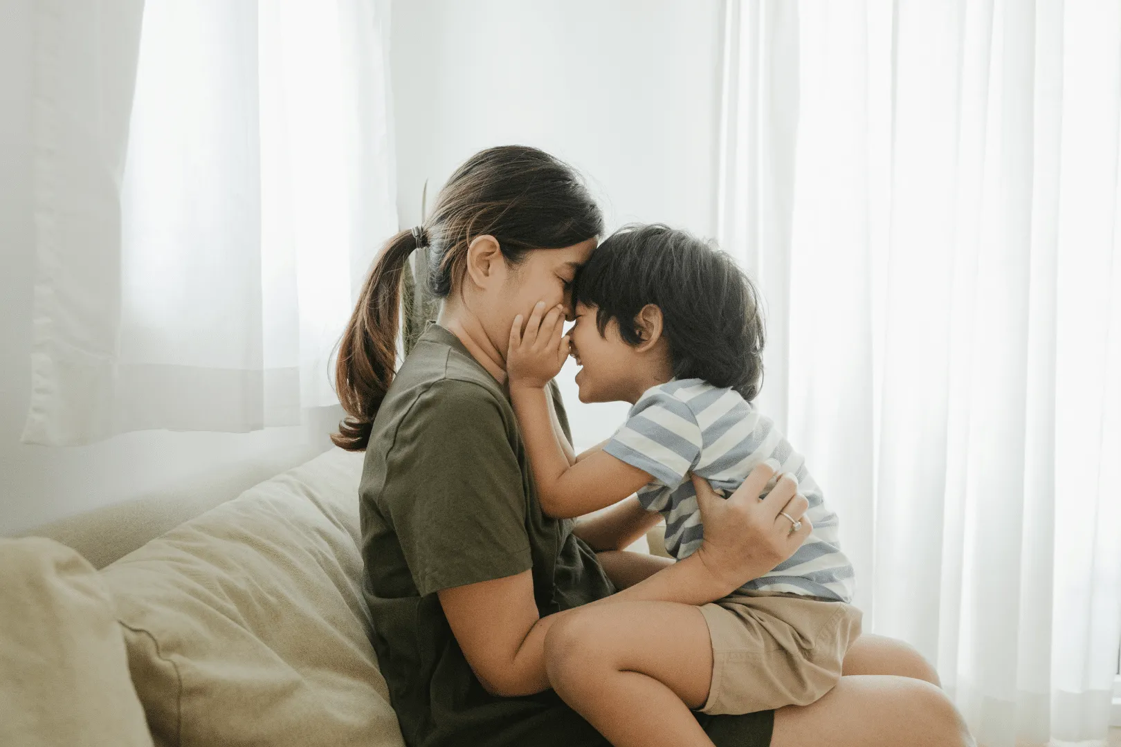 Mom hugging younger son smiling touching faces