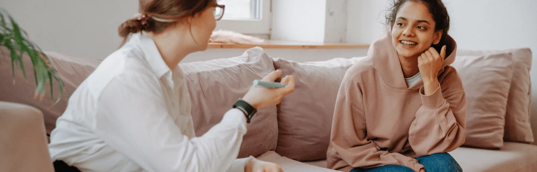 Female therapist and engaged teenage girl in therapy session sitting on a couch