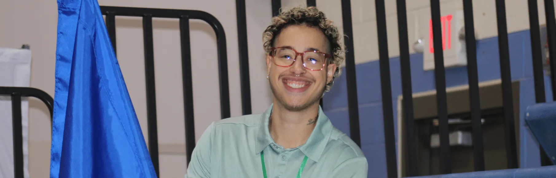Bi-racial young man with brown glasses and curly blonde tipped hair smiling