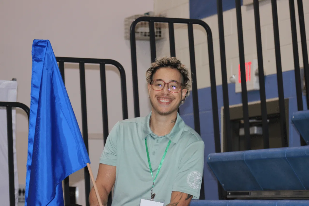 Bi-racial young man with brown glasses and curly blonde tipped hair smiling