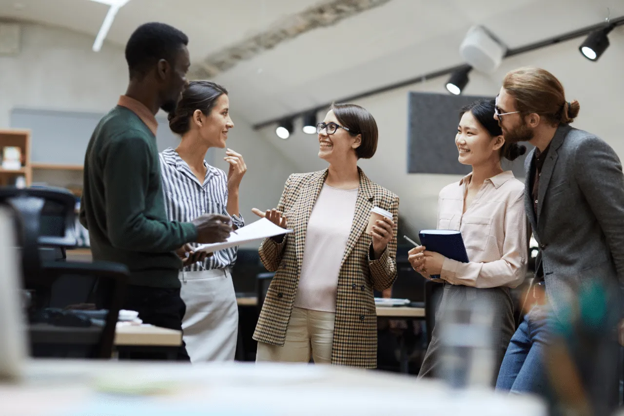 Social workers standing, smiling talking together in an office setting