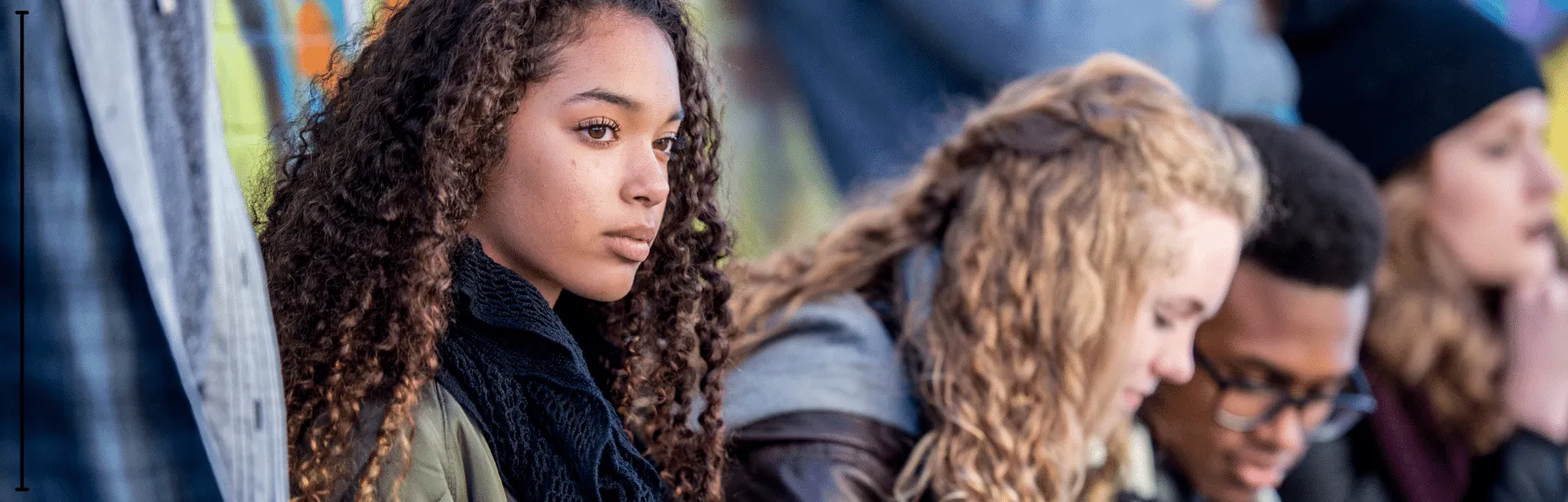 Teen girl looking away serious sitting with a group of teens