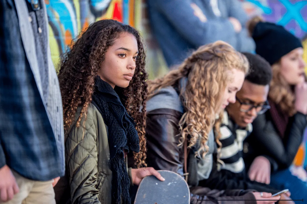 Teen girl looking away serious sitting with a group of teens