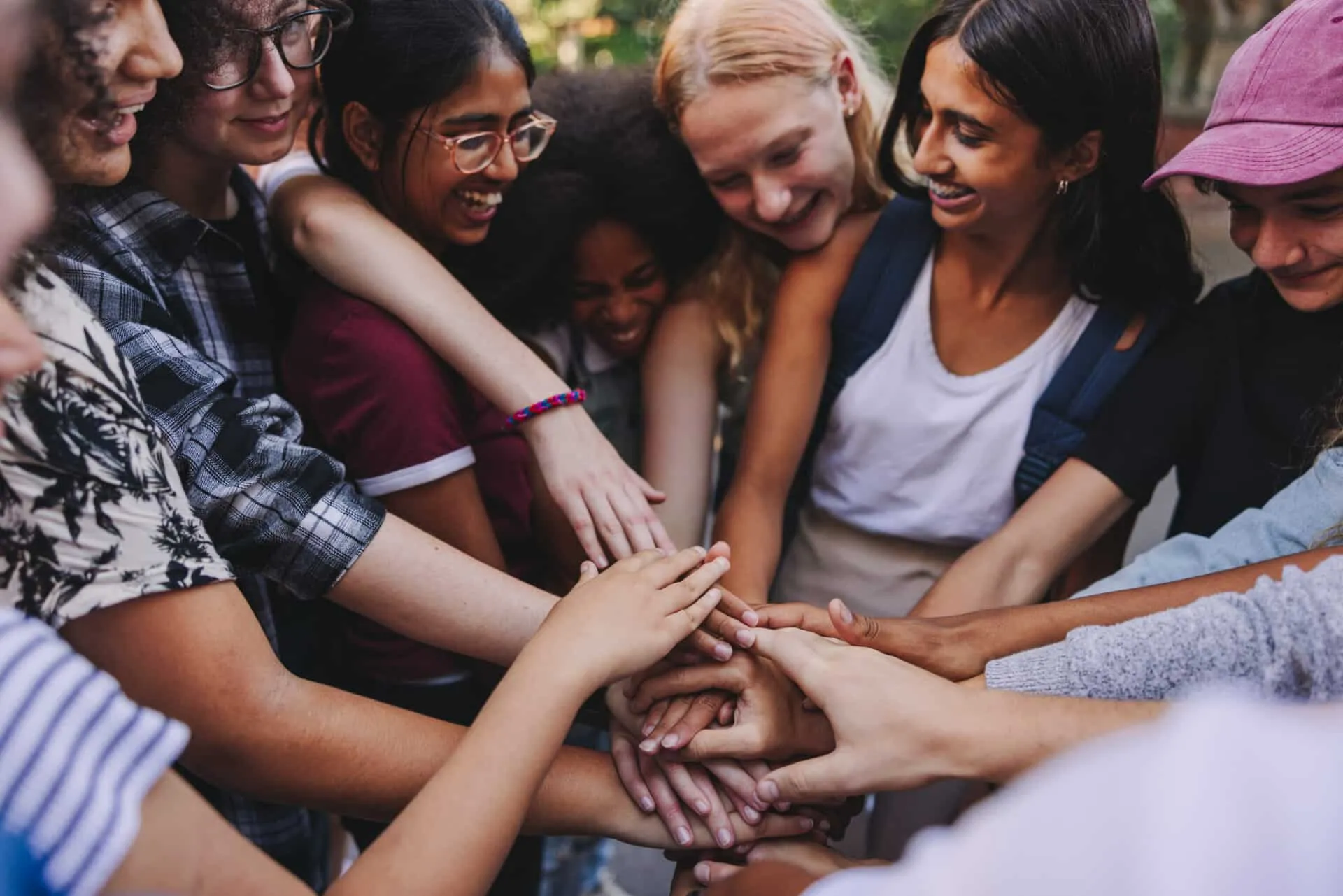 Smiling teens circling around with hands in middle