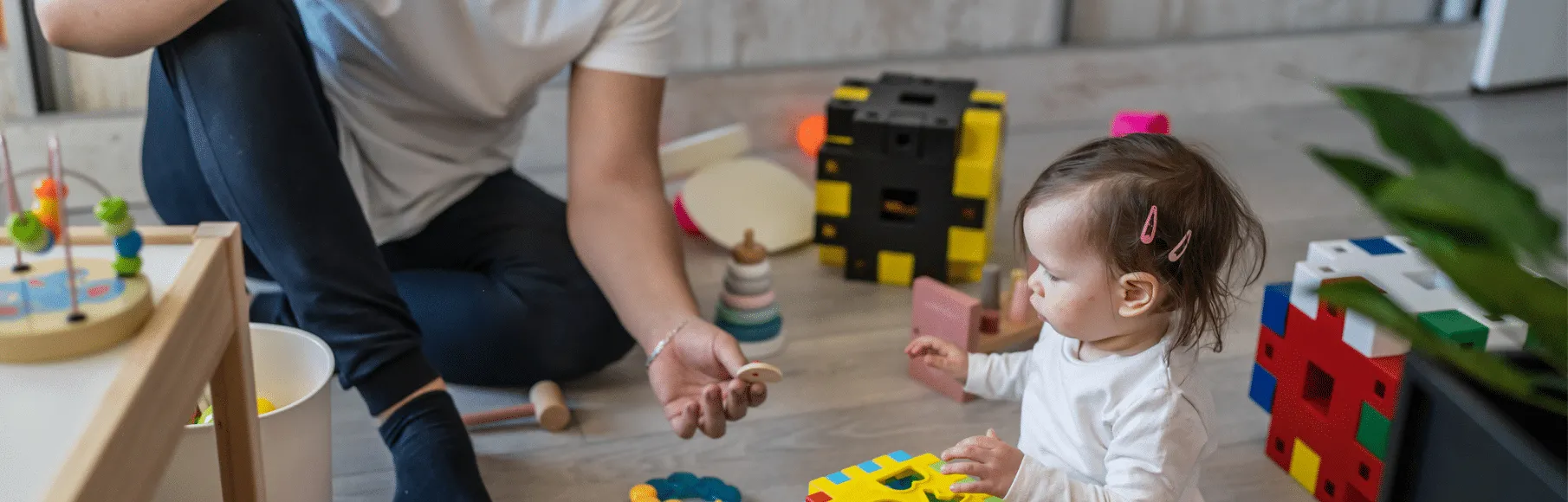 Dad handing young daughter a small wooden toy to hold and play with