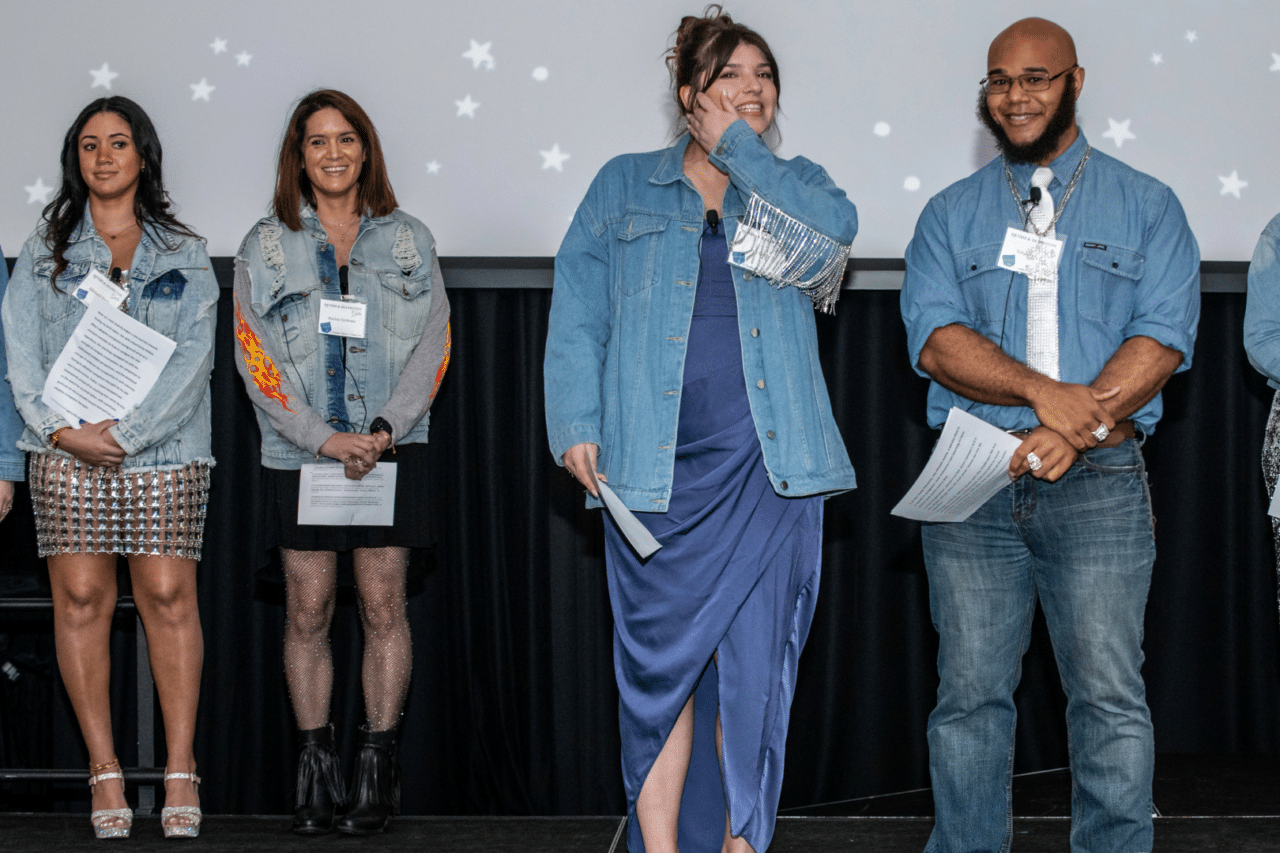 Michaela Battle and Rachel Shifaraw smiling in background looking at Zoe Bulitt and Tony Parson smiling on stage