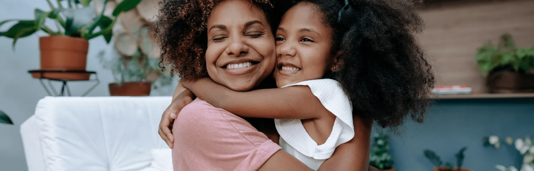 Black young woman hugging black young girl smiling
