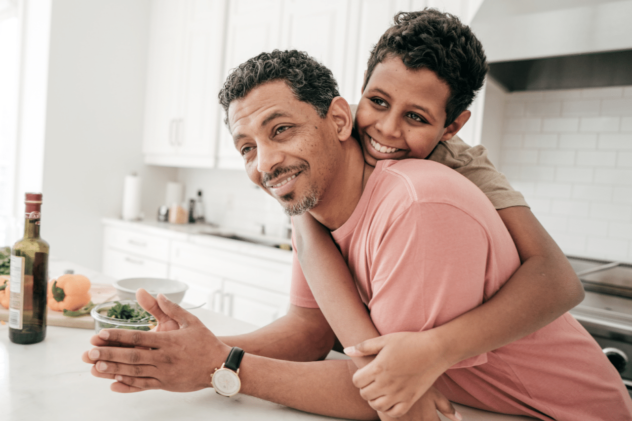 Son Hugging Father in Kitchen