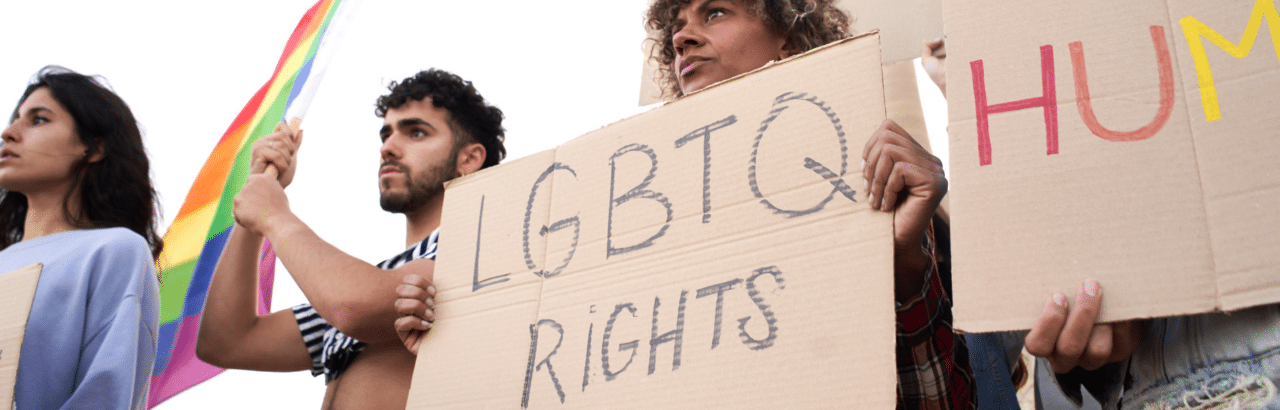 Women holding cardboard box sign with LGBTQ Rights in black marker