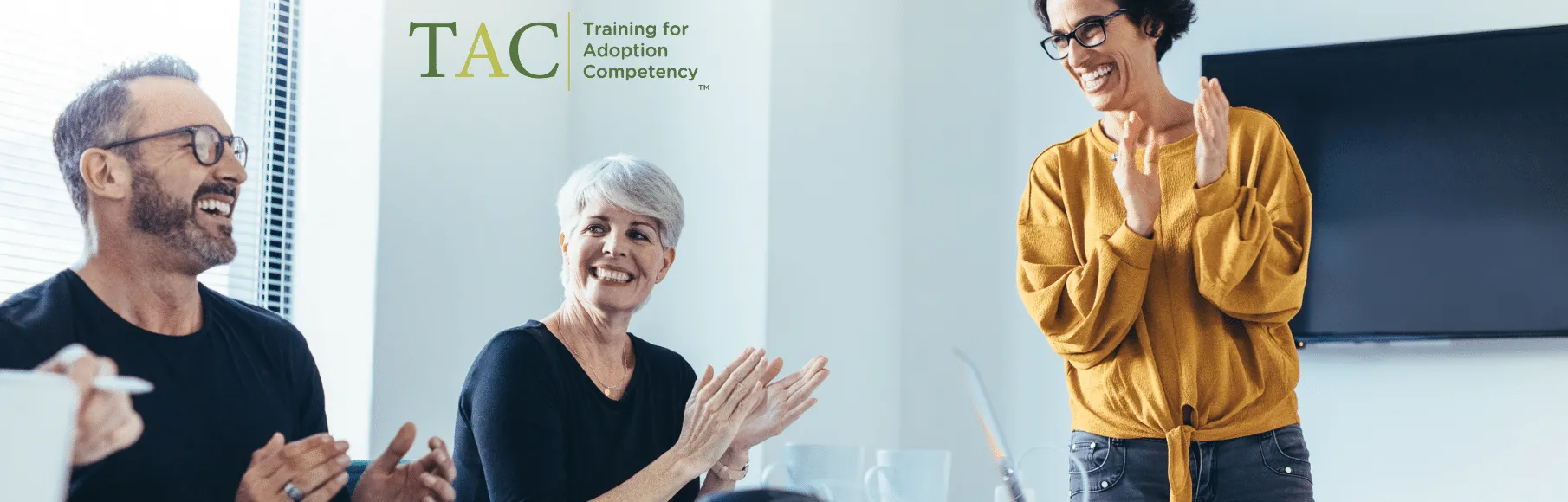 Professionals smiling and clapping in conference room setting, TAC logo overlay