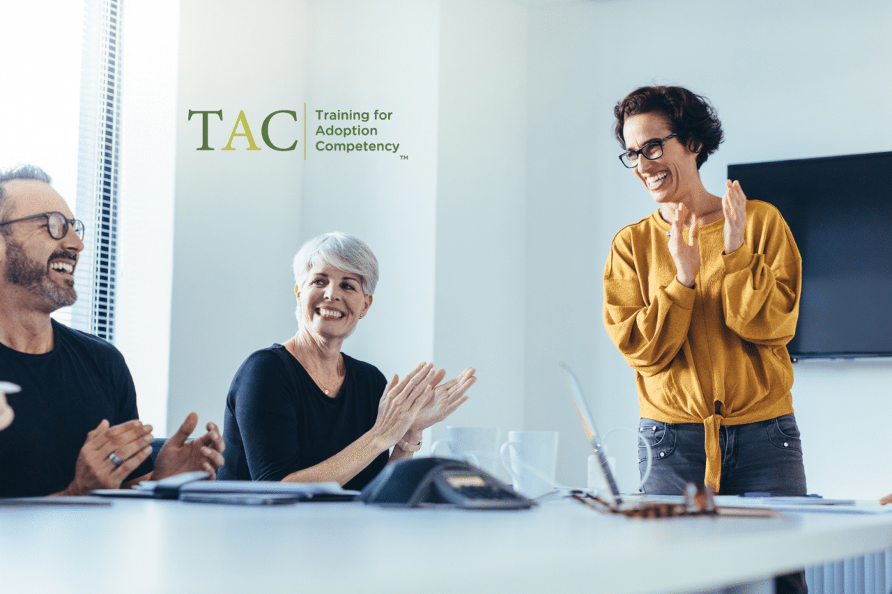 Professionals smiling and clapping in conference room setting, TAC logo overlay