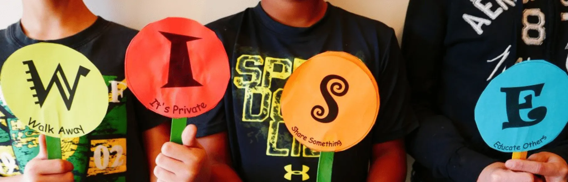 Kids holding up different color paper cut outs W.I.S.E. for W.I.S.E. Up!