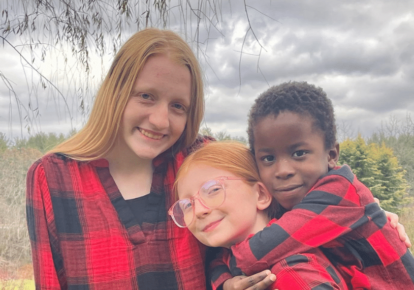 Three smiling kids dressed in buffalo plaid flannel