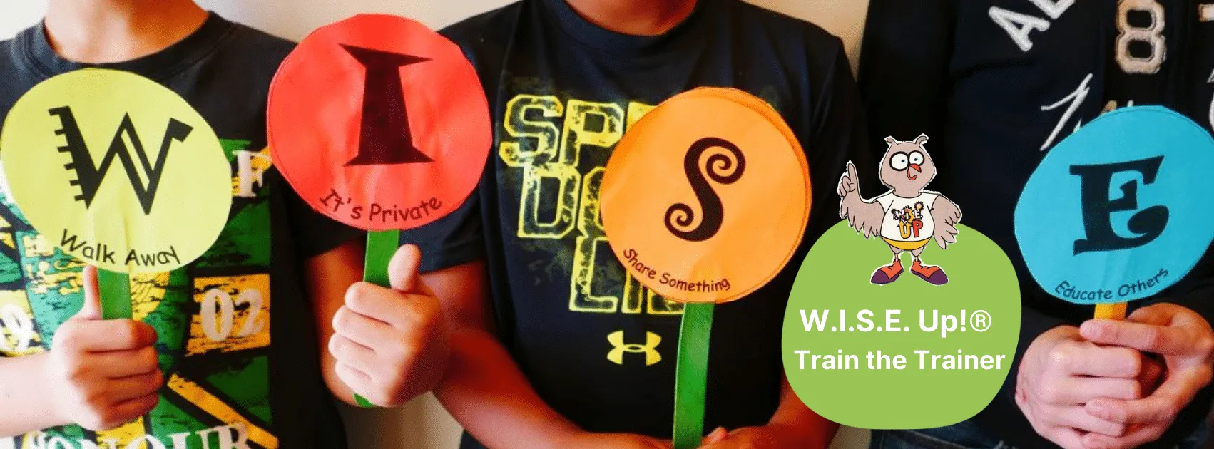 Kids holding up different color paper cut outs W.I.S.E. for W.I.S.E. Up! Train the Trainer