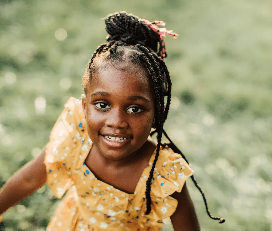 Young black girl in yellow dress smiling at camera