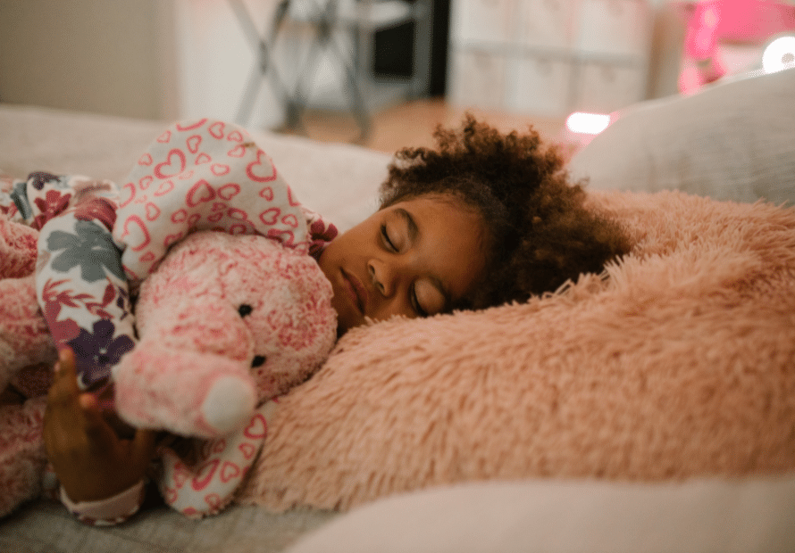 Young biracial girl sleeping on pink pillow holding pink elephant stuffed animal