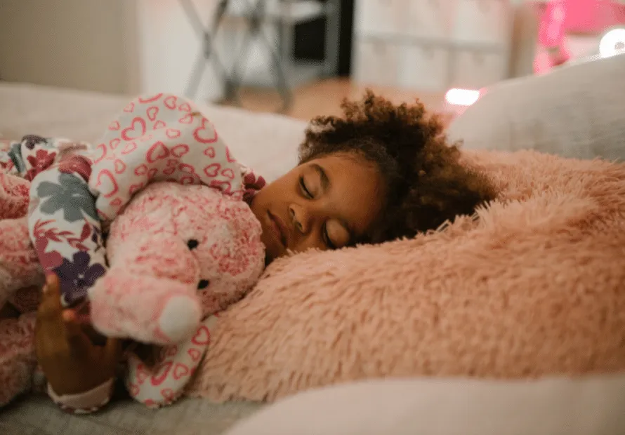 Young biracial girl sleeping on pink pillow holding pink elephant stuffed animal
