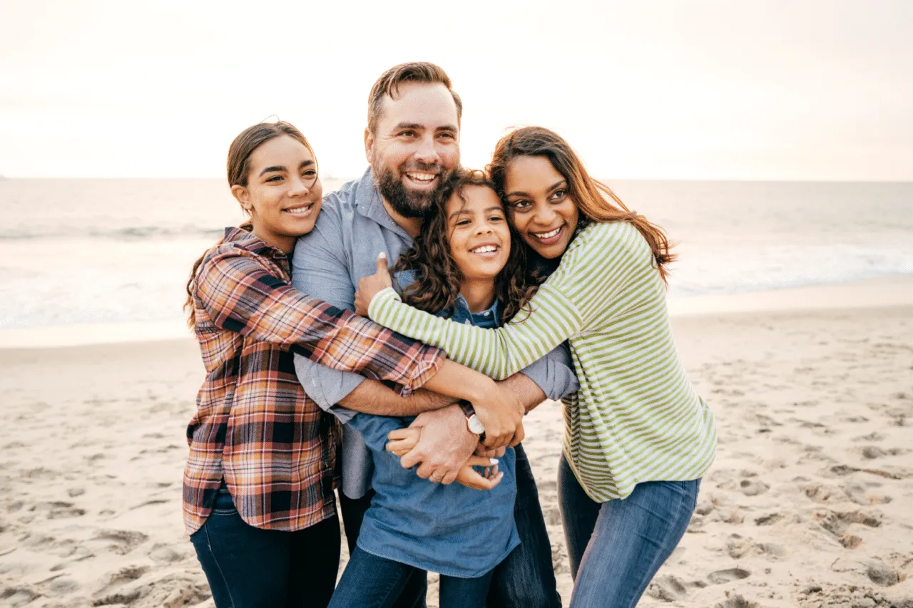 Family hugging and smiling on a beach together