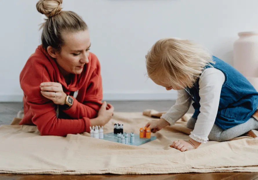 Birth mother playing game with daughter on the floor