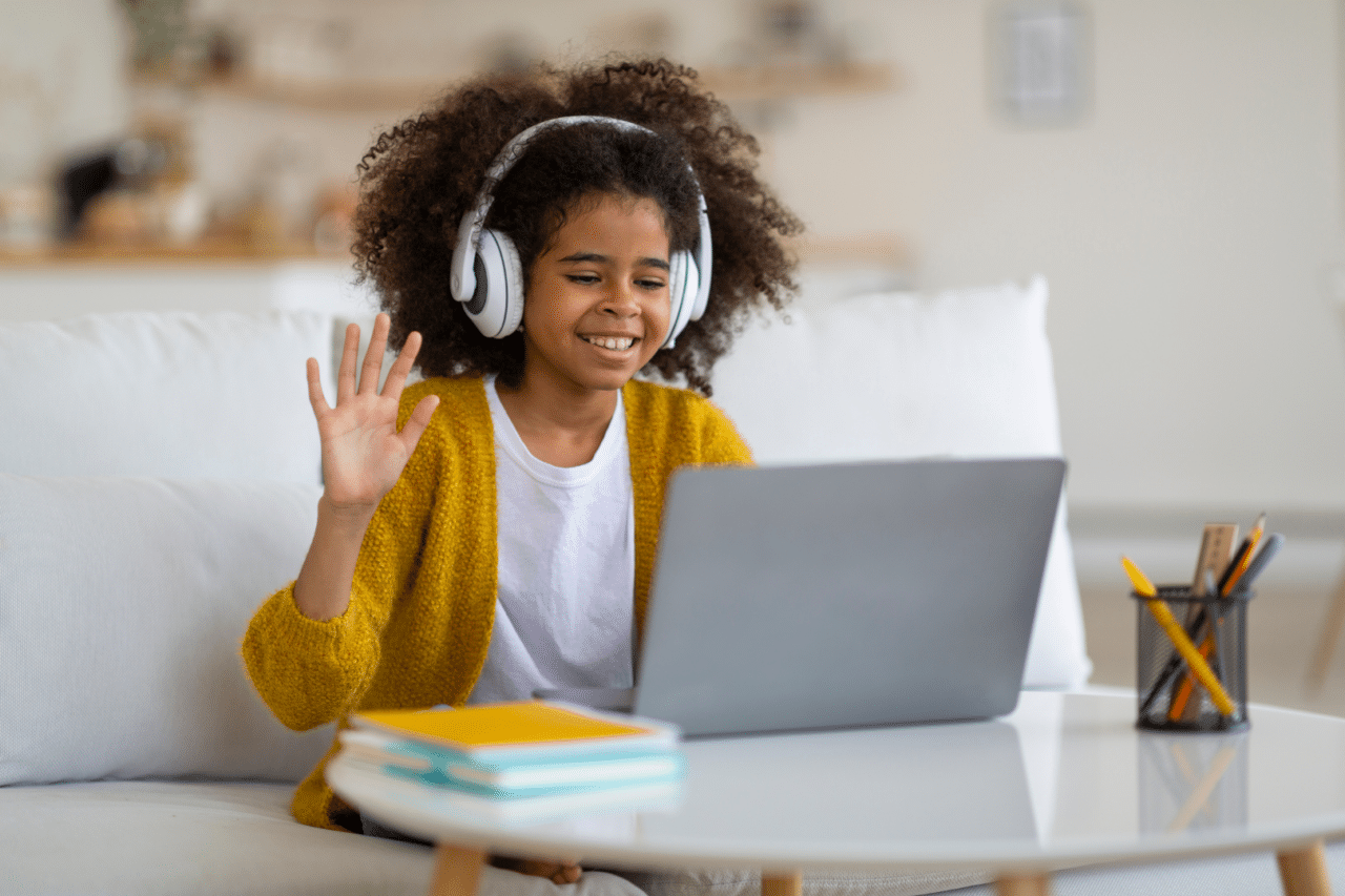 Young Bi-Racial Girl Wearing Headphones Waving and Interacting on Virtual Support Group