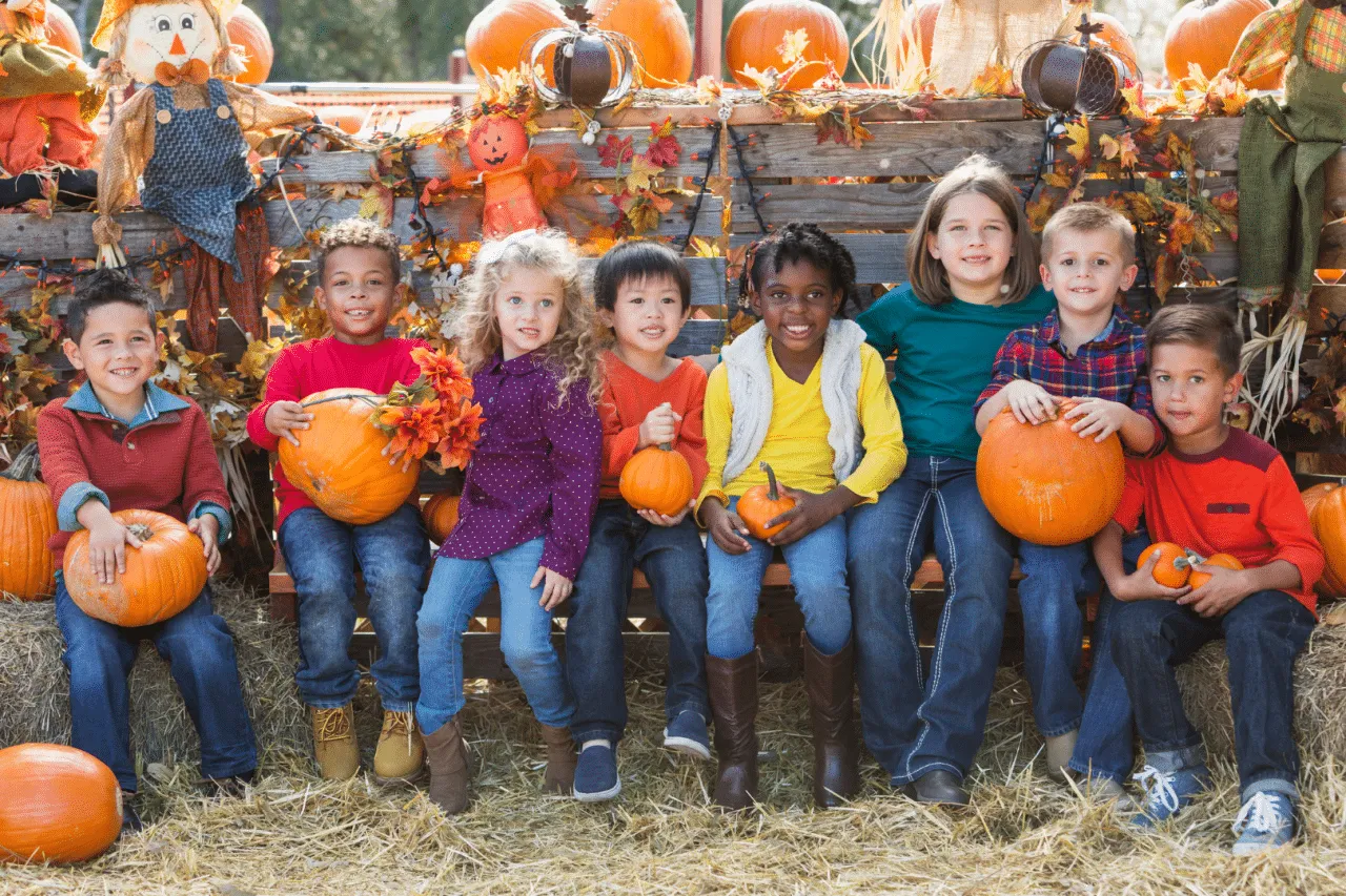 Diverse Group of Kids Smiling and Holding Pumpkins